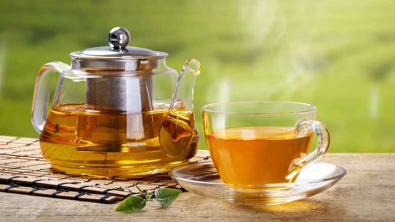 Warm,Cup,Of,Tea,With,Teapot,,Green,Tea,Leaves,On